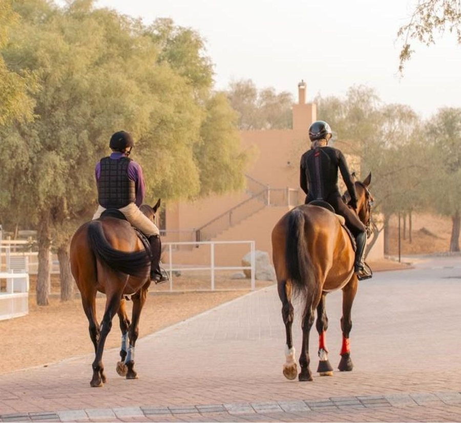 Two riders on the pathway at Al Wadi Equestrian Center